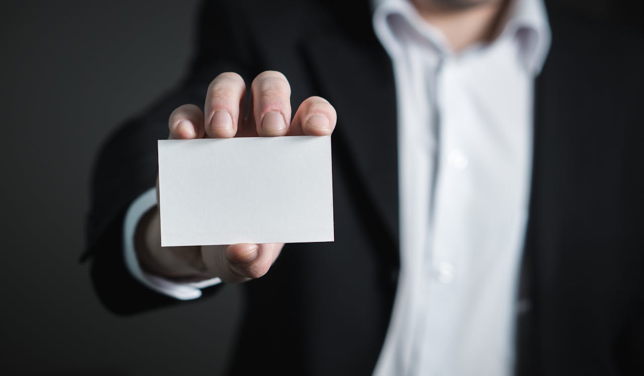 A man in a suit presenting a blank business card for corporate usage.